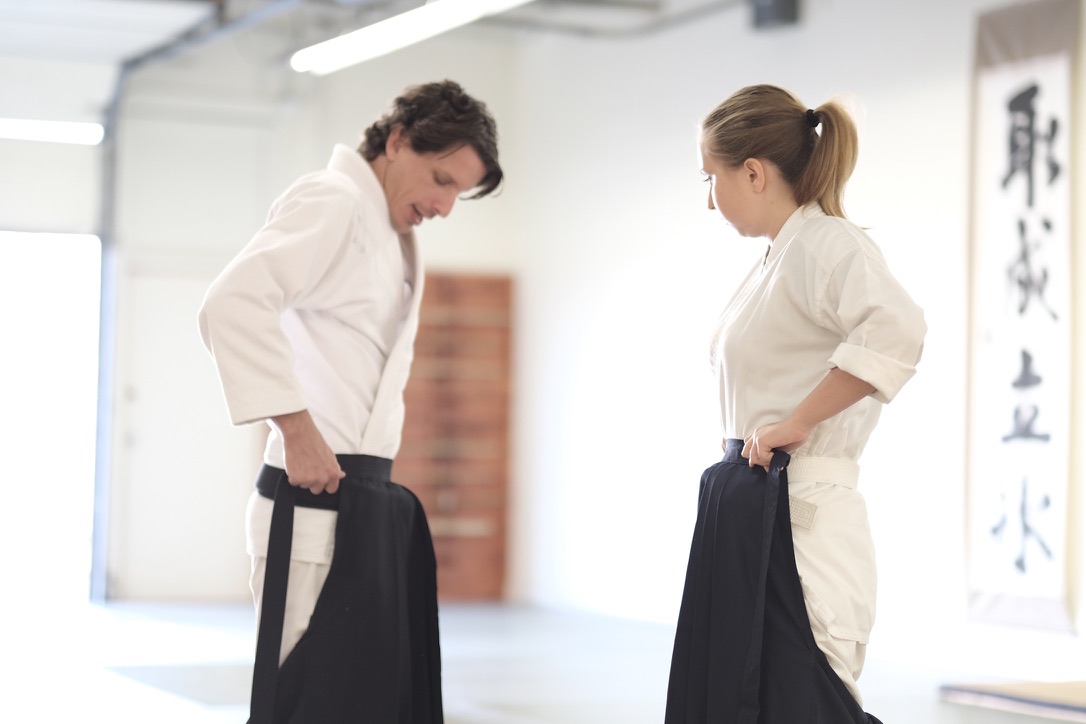 Josh Gold and a student tie their hakama side by side.